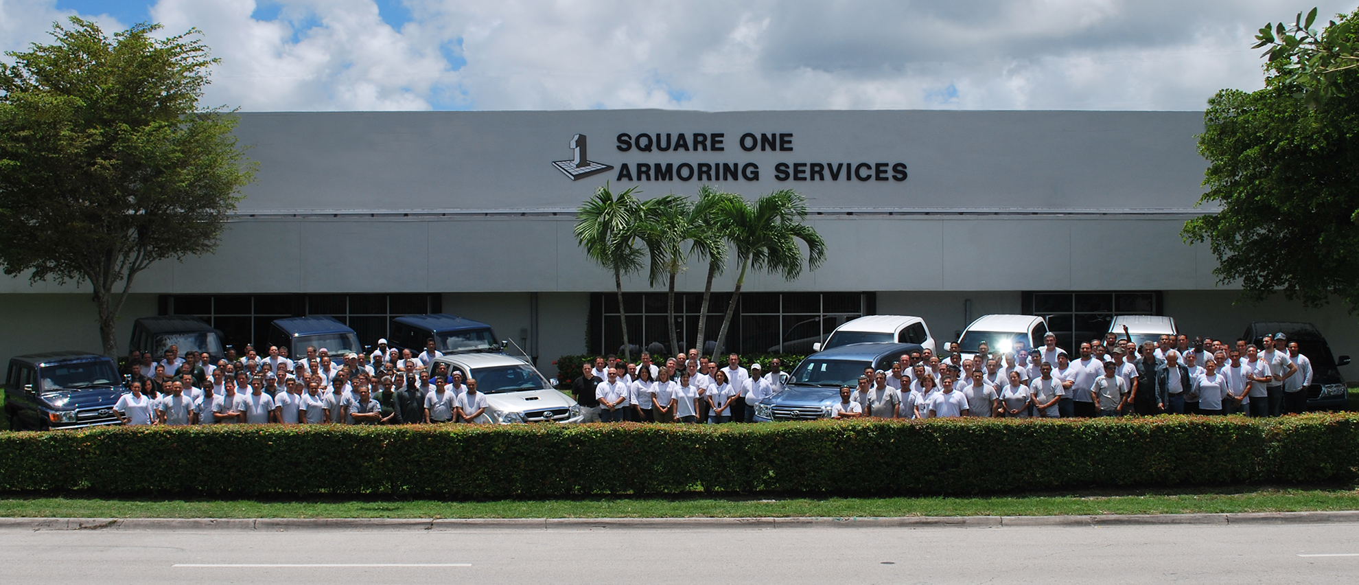 White up-armoured Toyota Land Cruiser 300 Series on a dusty urban road